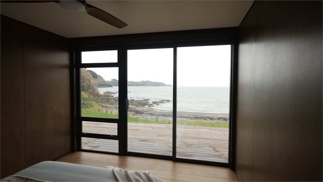 Modern bedroom overlooking coastal views with awning window and sliding door